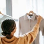 Woman shopping for stylish stock clothing in a boutique, holding various outfits and accessories.